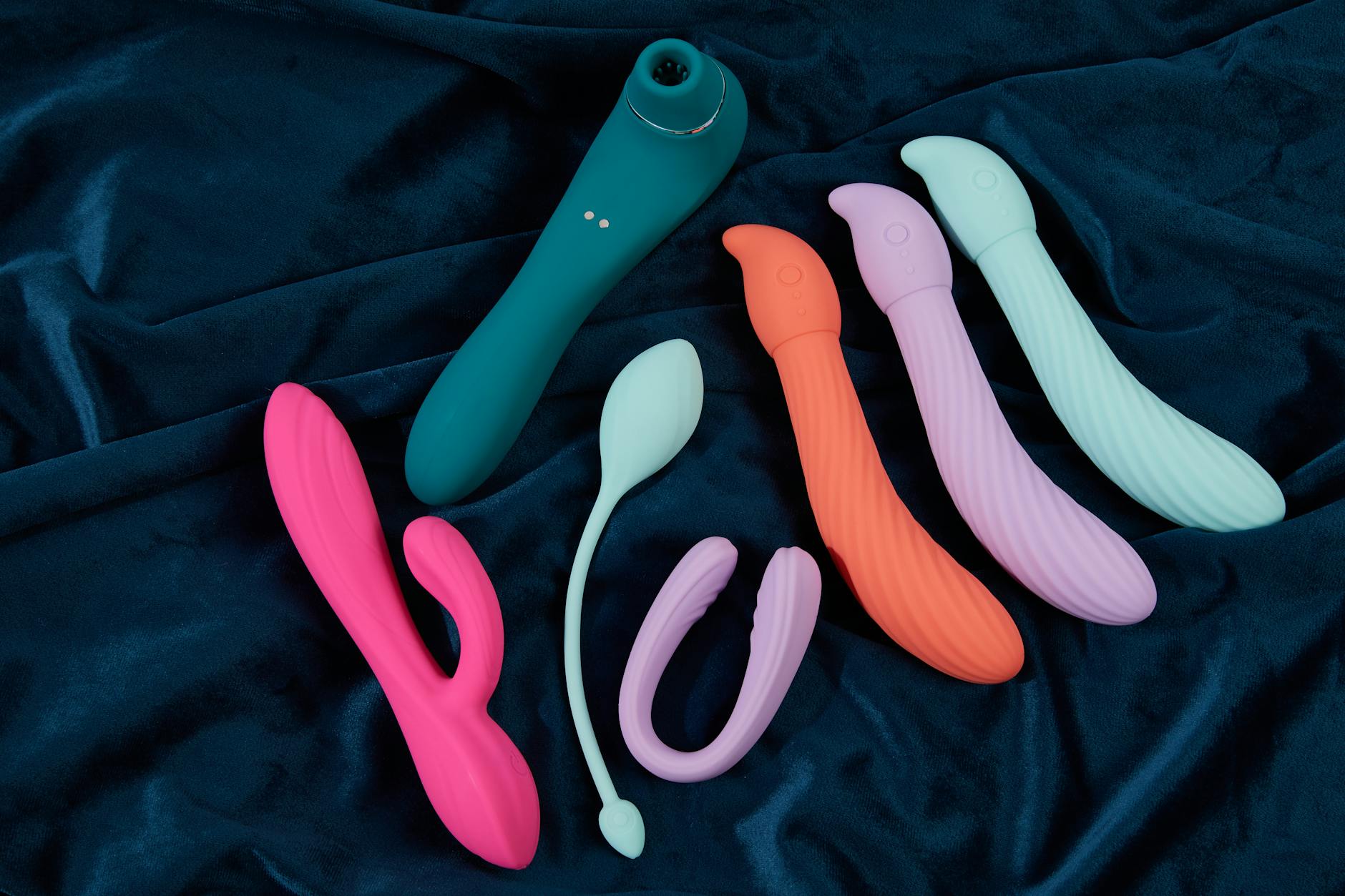 Hand holding a blue silicone vibrator over a decorative glass bowl