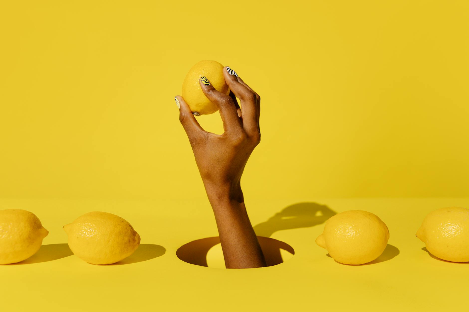 Close-up of hands holding a lemon vibrator and personal massager against a knitted sweater