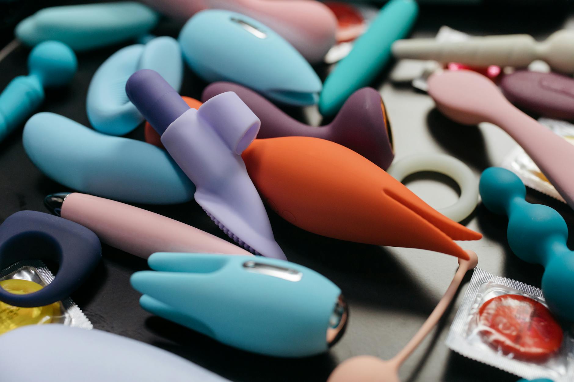 Woman holding colorful clitoral vibrators with a thoughtful expression