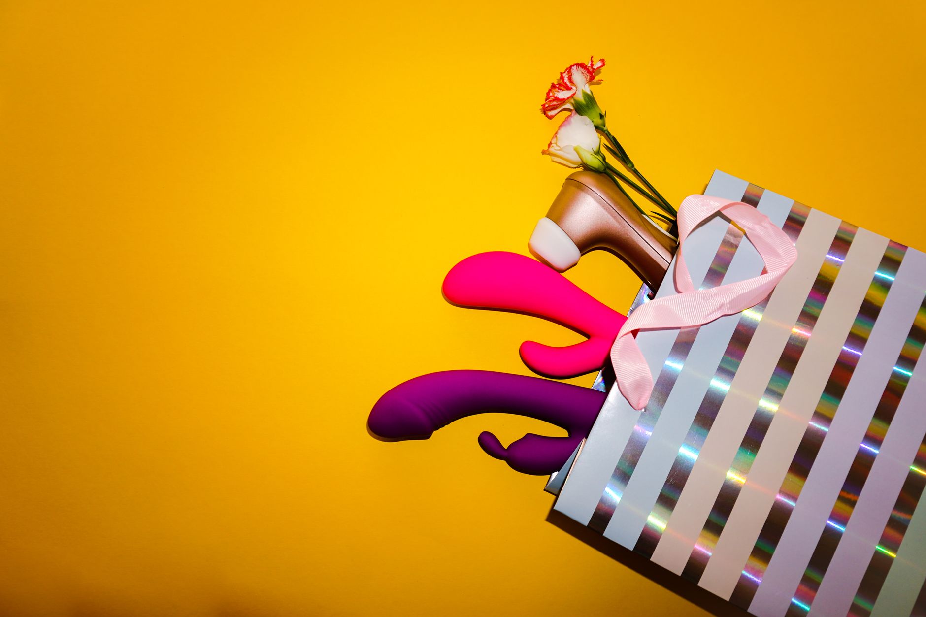 A hand reaching over a variety of colorful lemon clitoral vibrators arranged on a table.
